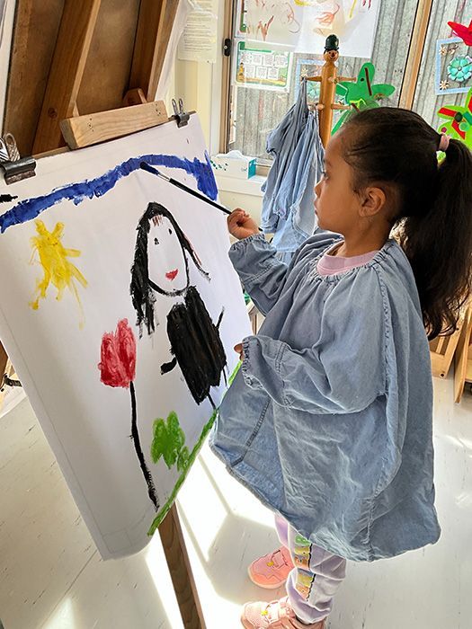 Young child interacting with a light table, placing colorful shapes on it.