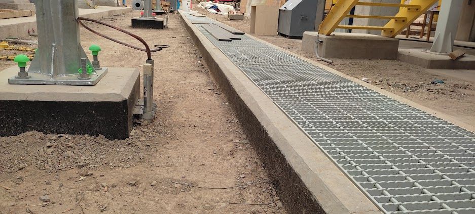 Taller industrial con trabajadores, estructuras metálicas rojas y grúas aéreas en una gran nave industrial.