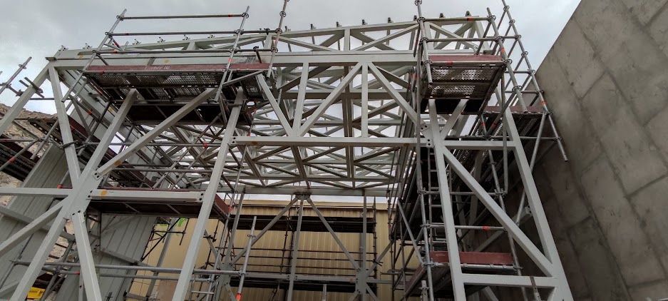 Trabajador con casco naranja manejando una máquina en un taller de fábrica.