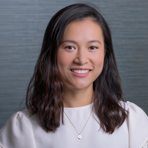 Woman with dark hair smiles, wearing a white top and gold necklace.