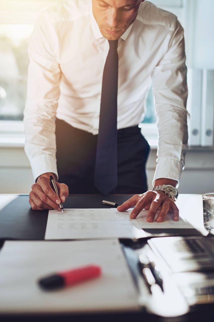 a man in a suit and tie is signing a document at a desk