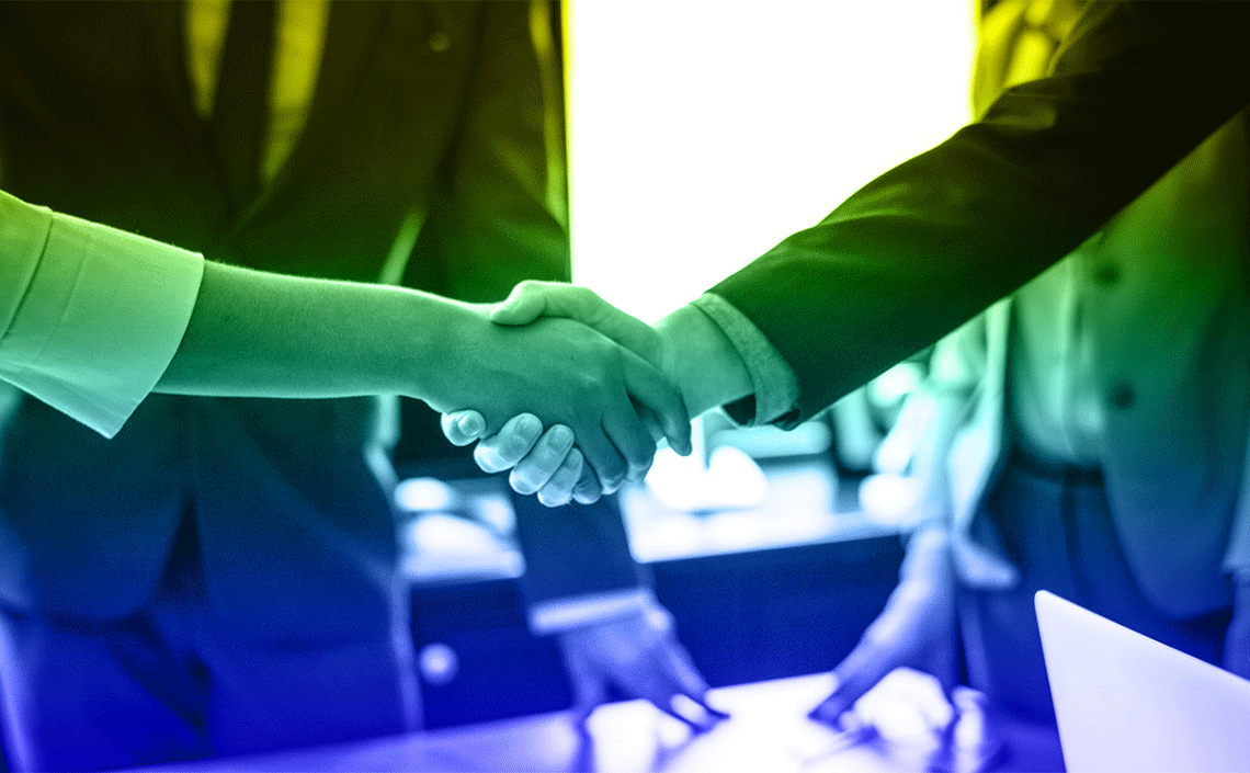 A man and a woman are shaking hands over a table.