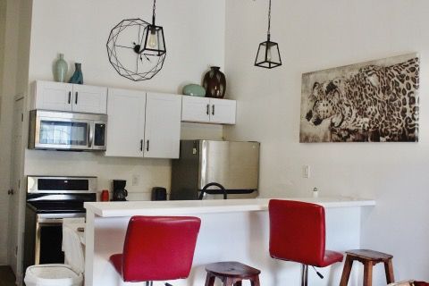Kitchen with white cabinets, red barstools, and stainless steel appliances.