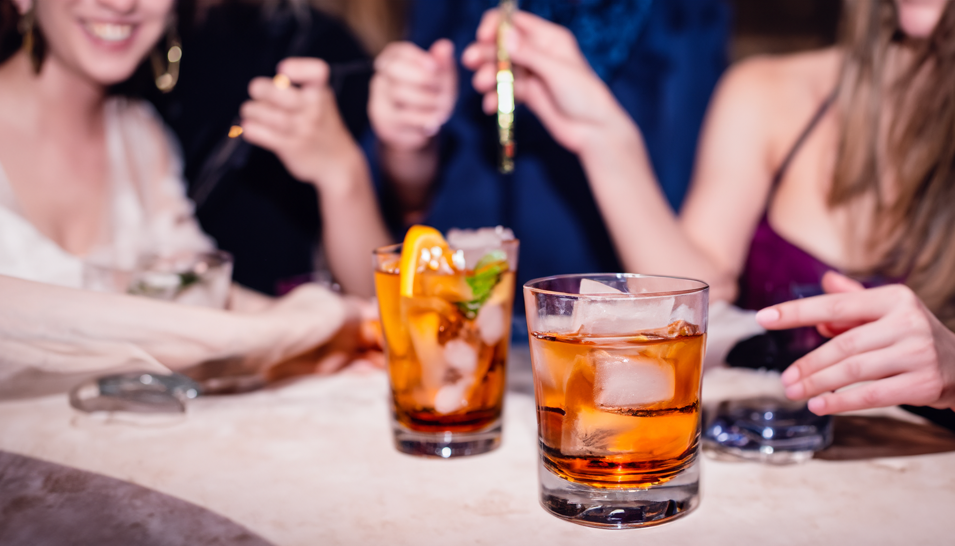A group of people are sitting at a table with drinks and cigarettes.