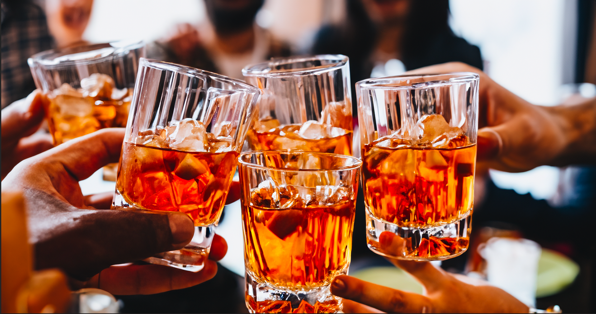 A group of people are toasting with glasses of whiskey.