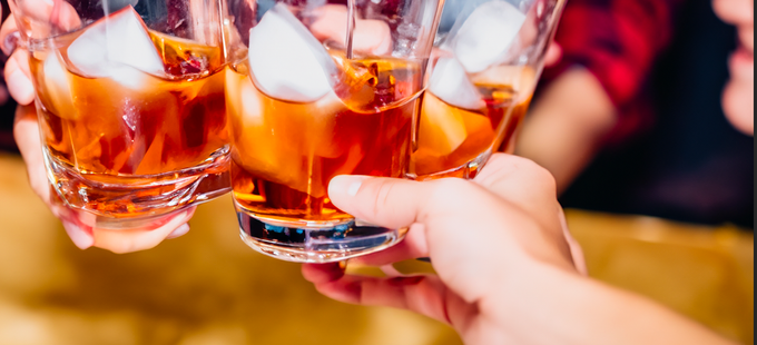 A group of people are holding glasses of whiskey with ice cubes.