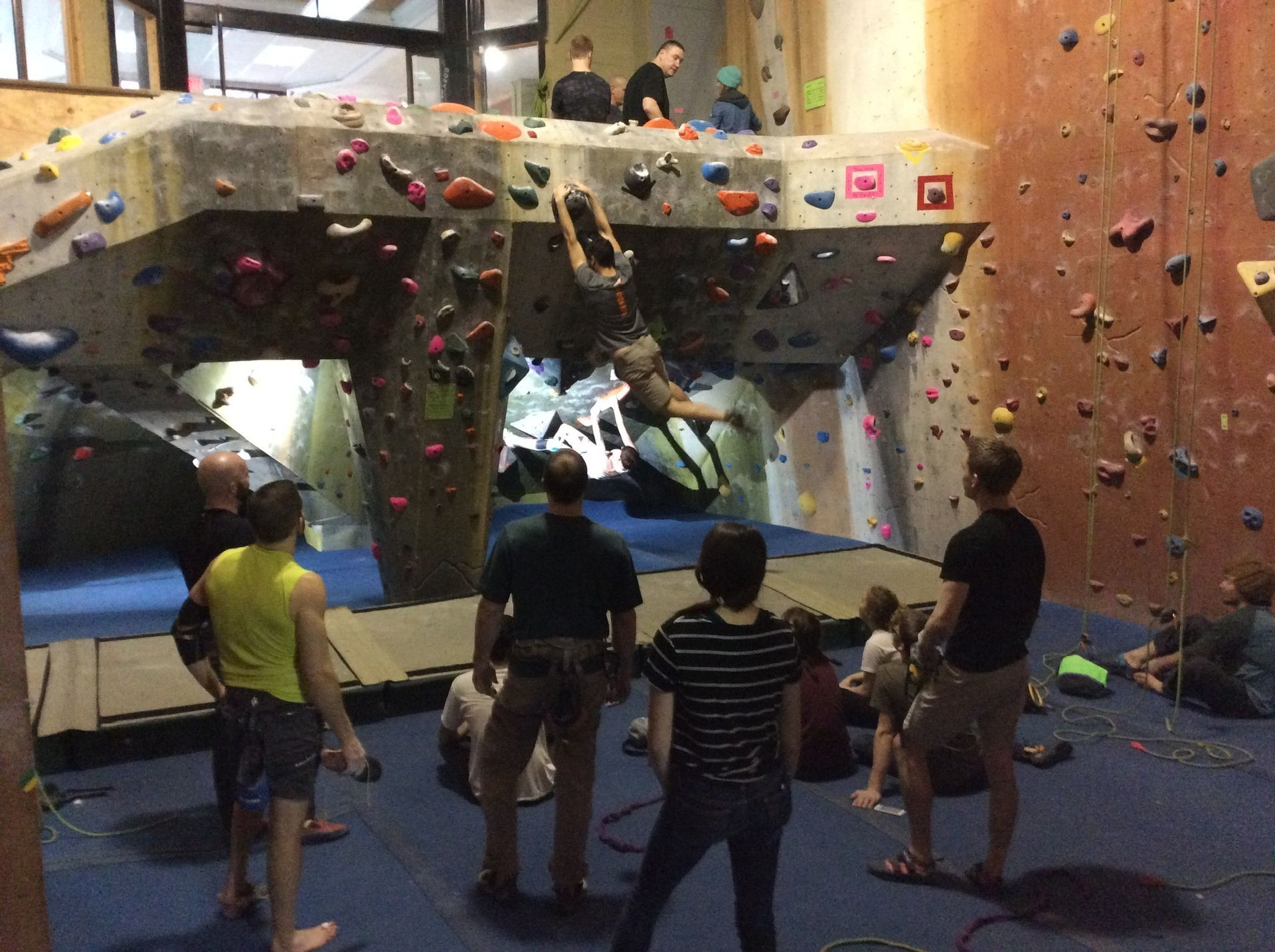 A group of people are standing around a climbing wall