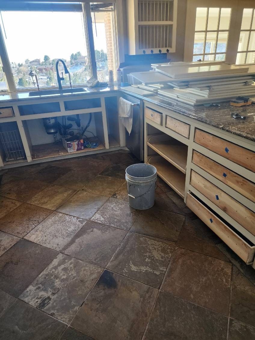 A kitchen with a sink and a trash can on the floor.
