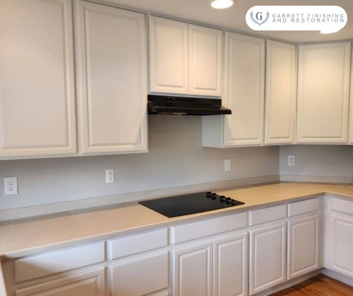 A kitchen with white cabinets and a stove top oven.