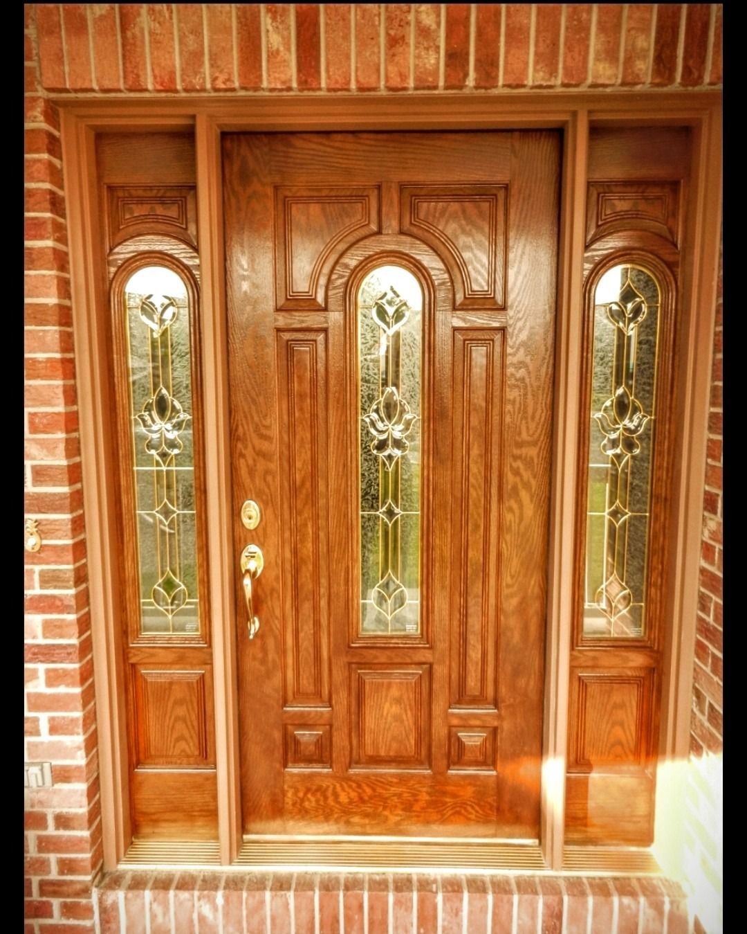 A wooden door with stained glass windows and a brick wall behind it