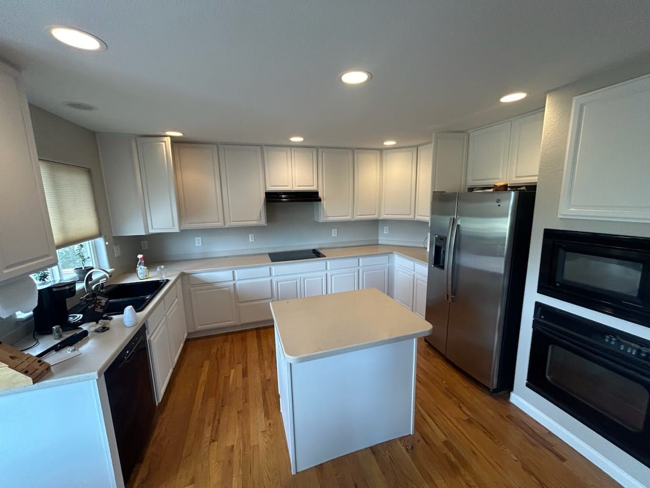A kitchen with white cabinets , stainless steel appliances , and a large island.