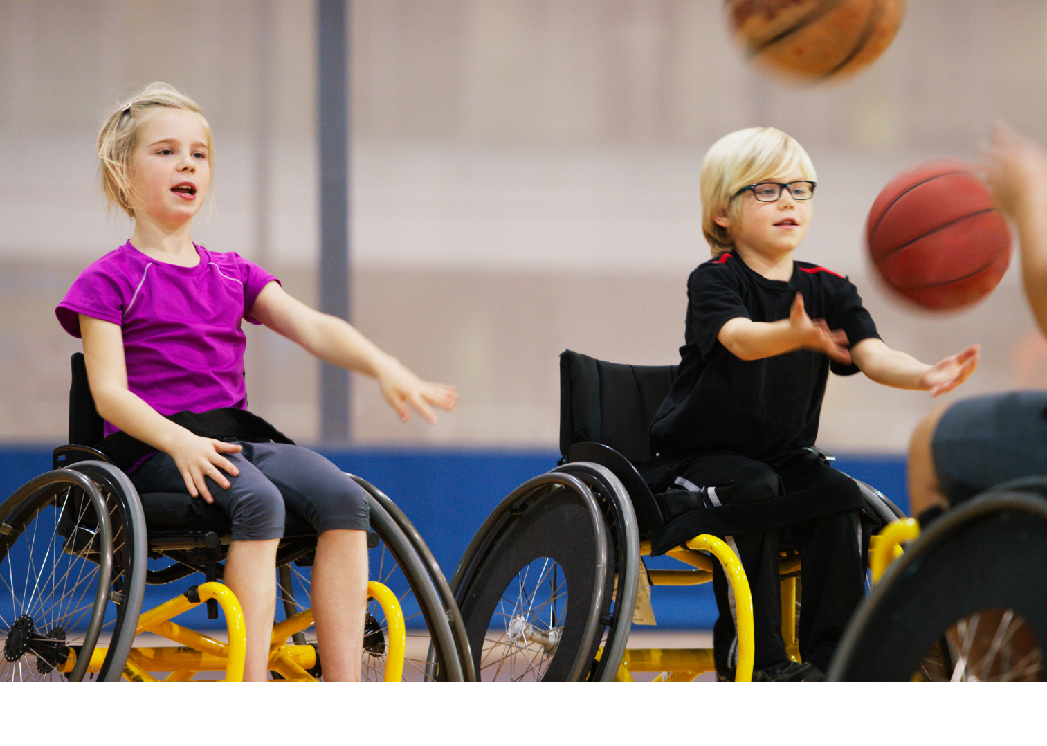 a boy and a girl in wheelchairs are playing basketball
