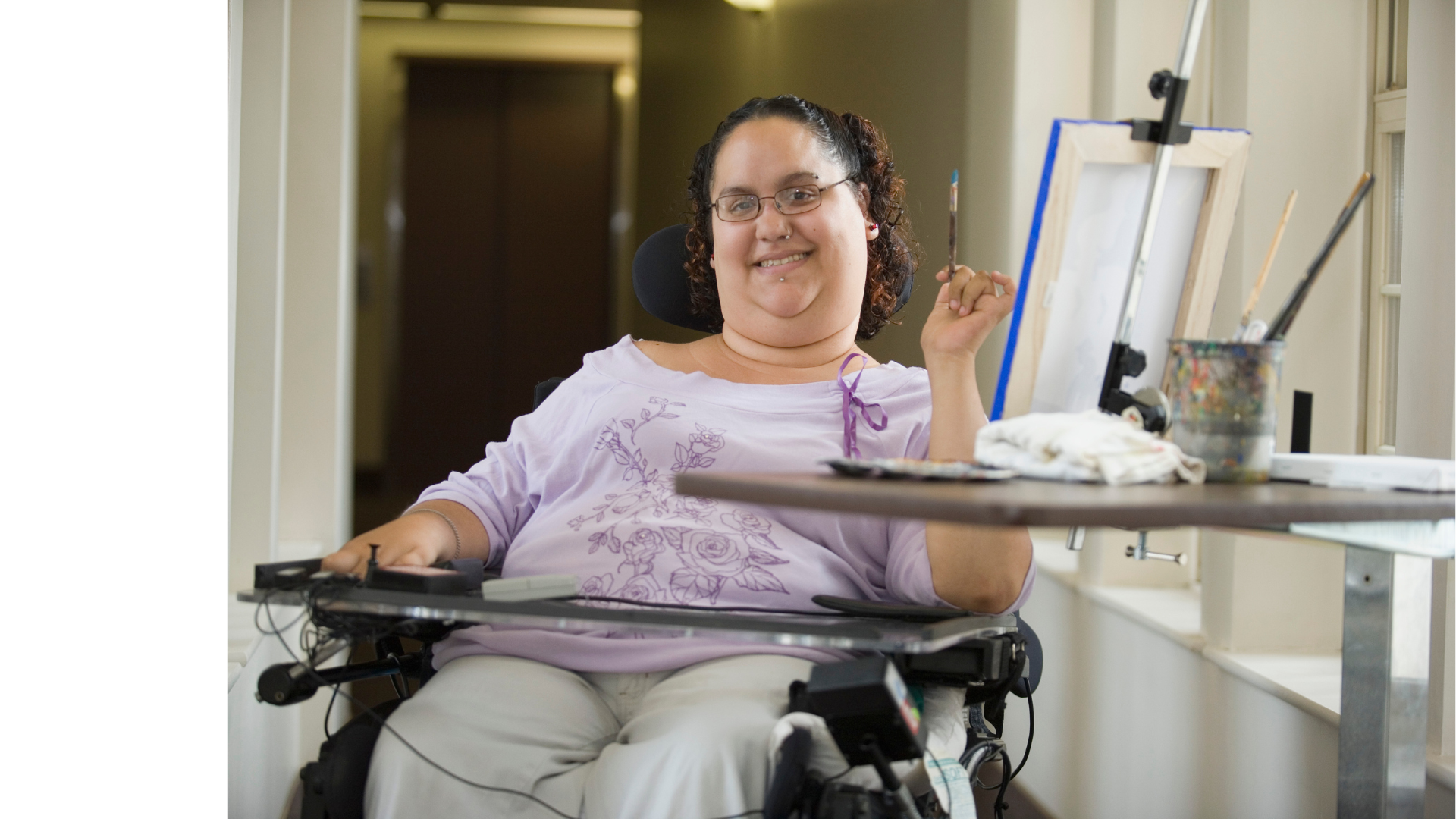 a woman in a wheelchair is smiling while sitting at a table .