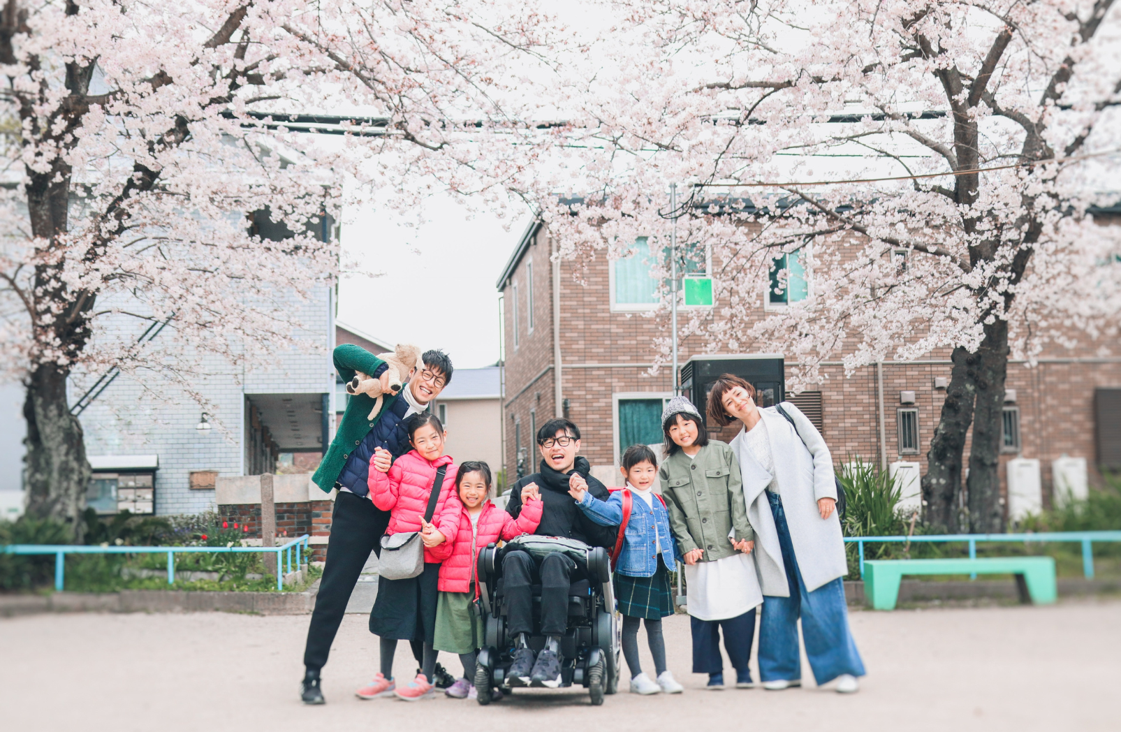 a group of people are posing for a picture in front of cherry blossom trees .