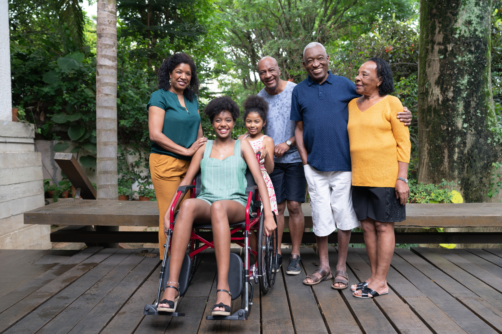 a group of people are posing for a picture with a girl in a wheelchair .