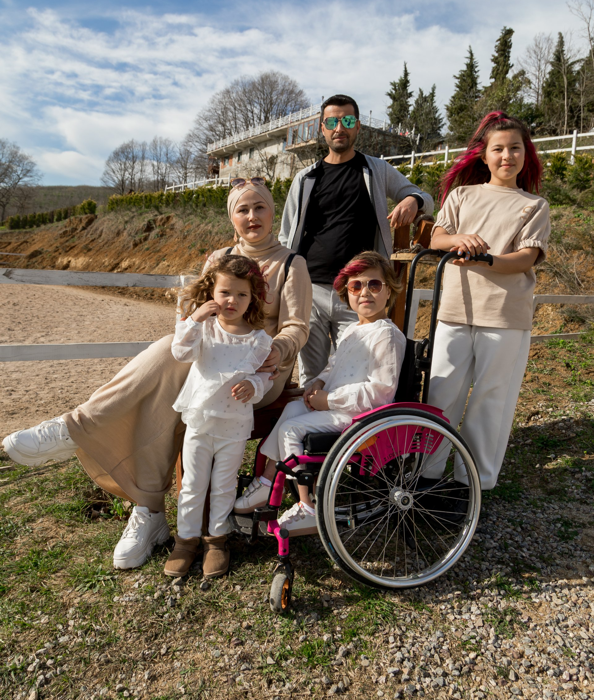 a family posing for a picture with a woman in a wheelchair .