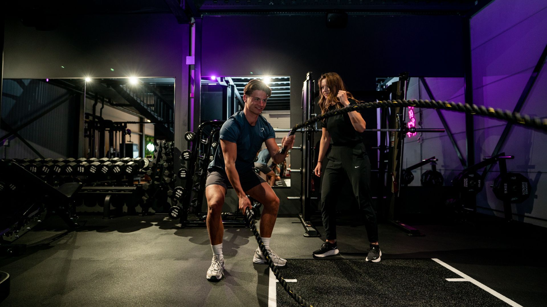 Een man en een vrouw spelen met touwen in een gymzaal.