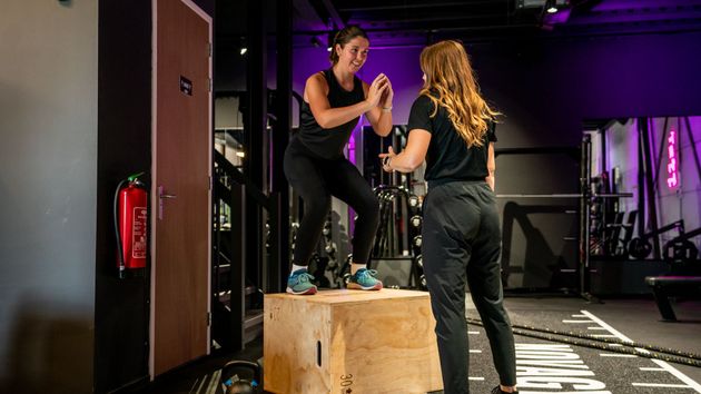 Twee vrouwen staan ​​op een houten kist in een gymzaal.