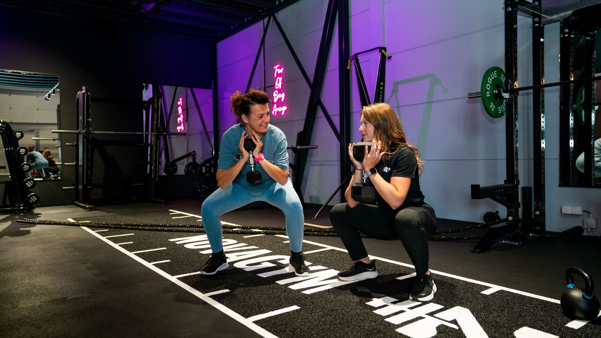 Een man en een vrouw doen squats in een sportschool.