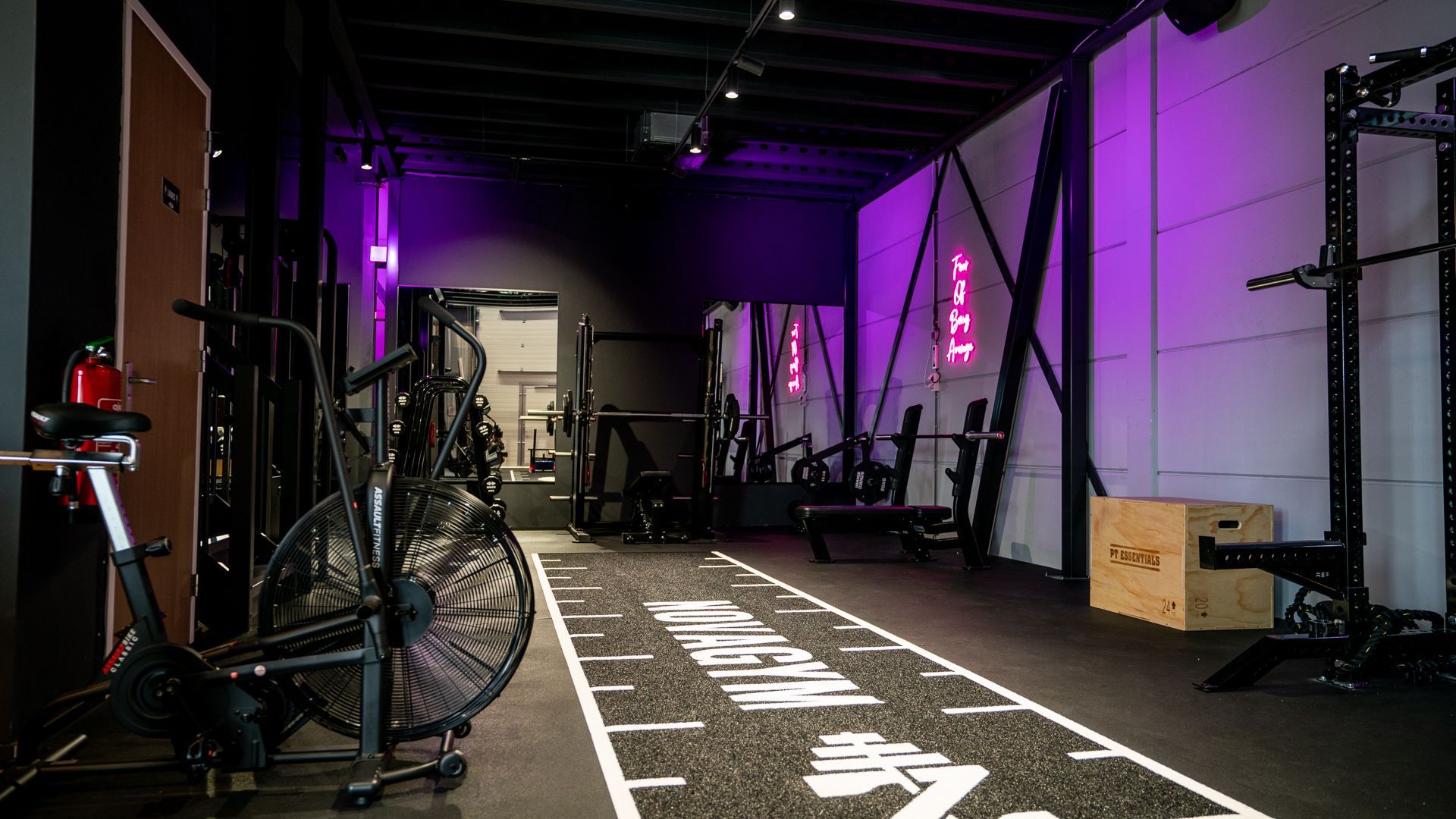 Een sportschool vol met fitnessapparatuur en een atletiekbaan.