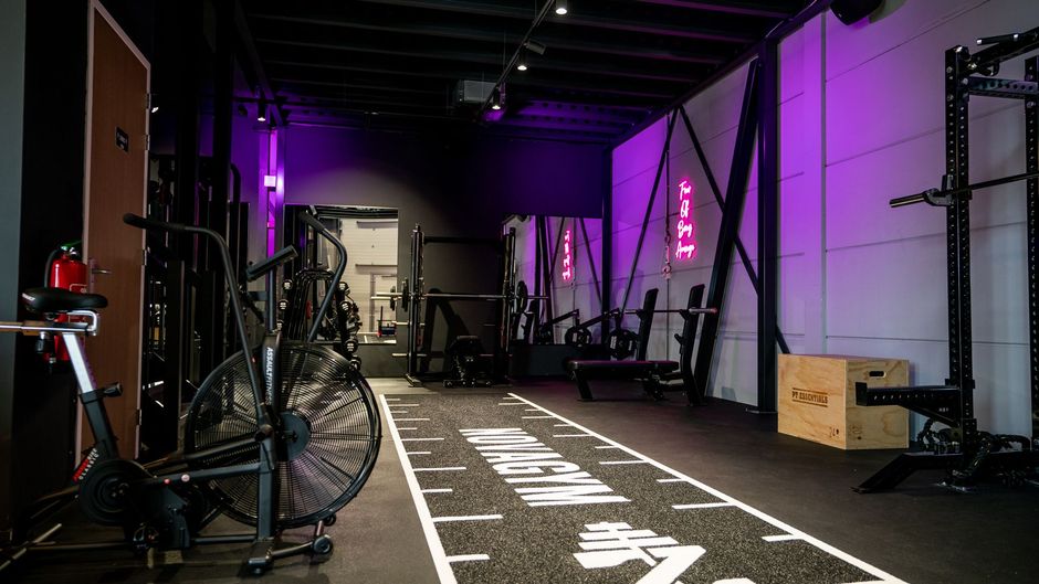 Een sportschool vol met fitnessapparatuur en een atletiekbaan.
