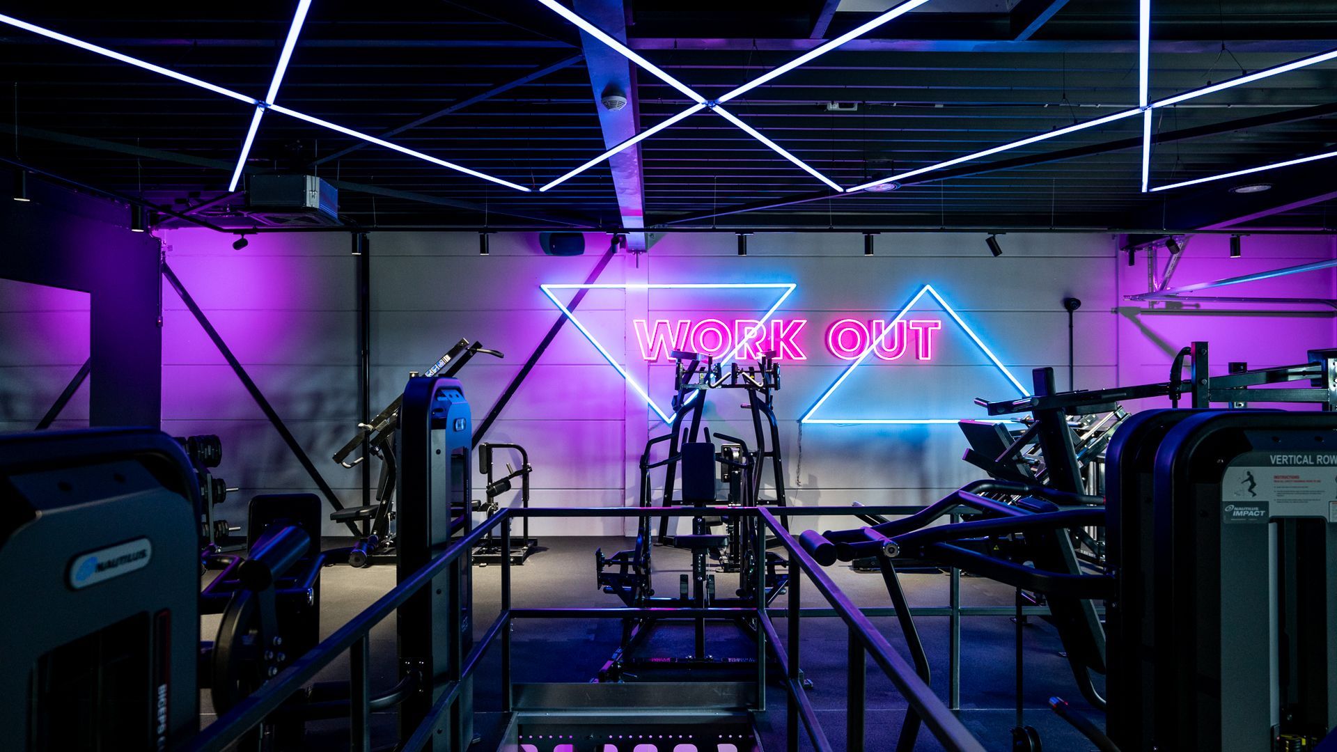 Een sportschool met een neonbord waarop 'work out' staat.