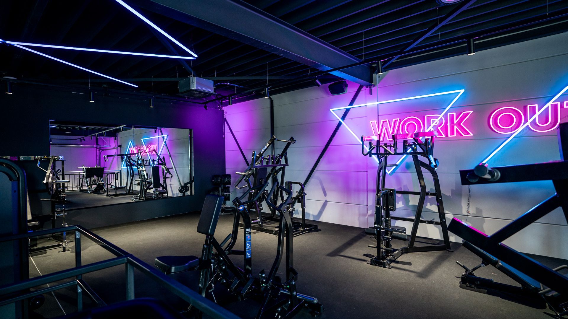 Een sportschool met een neonbord waarop 'work out' staat.