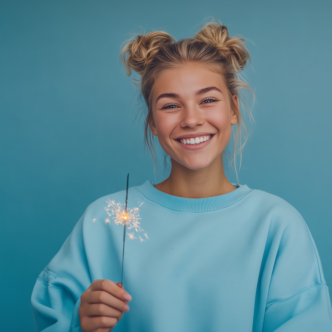 Woman with blonde buns smiles holding a sparkler against a blue background.