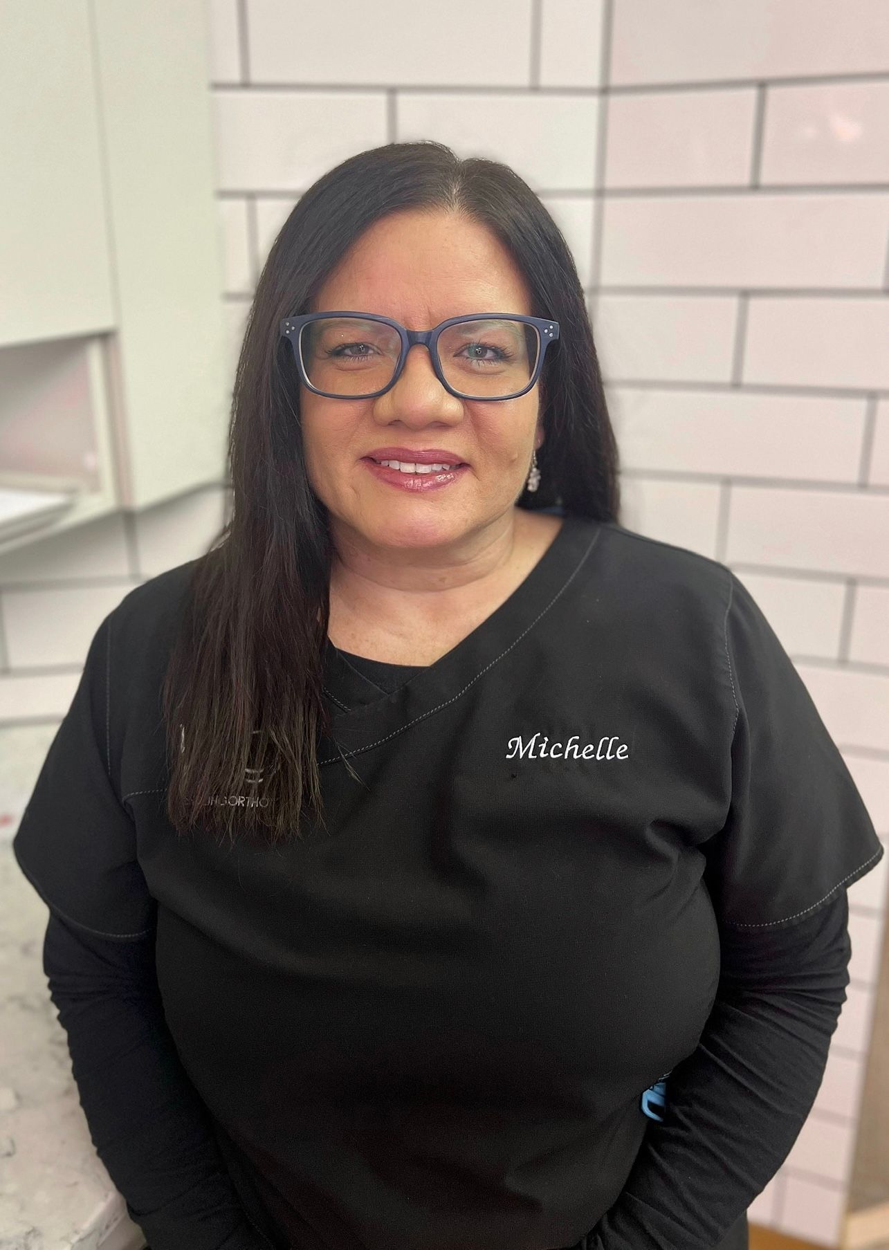A woman wearing glasses and a black shirt is smiling for the camera.