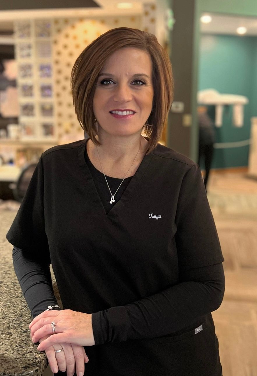 A woman in a black scrub top is standing next to a counter.