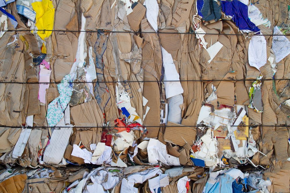 Baled cardboard and paper waste, compressed and bound with wire.