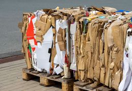 Cardboard and paper stacked on a wooden pallet, ready for recycling.