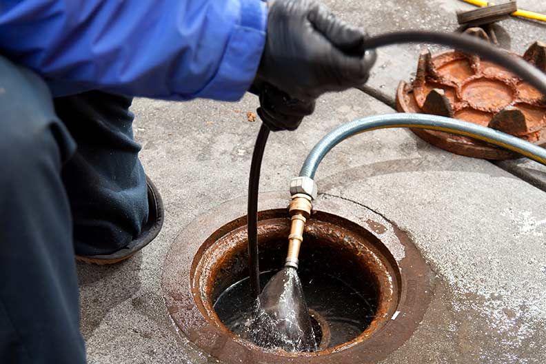 A man is cleaning a manhole cover with a hose.