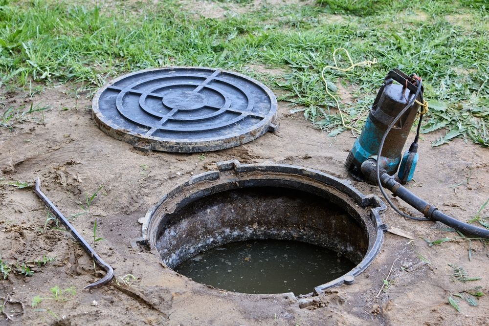 A manhole cover with a pump attached to it is open and filled with water.