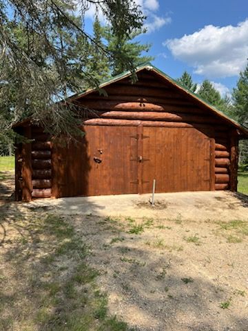 A large log cabin with a large garage in front of it.
