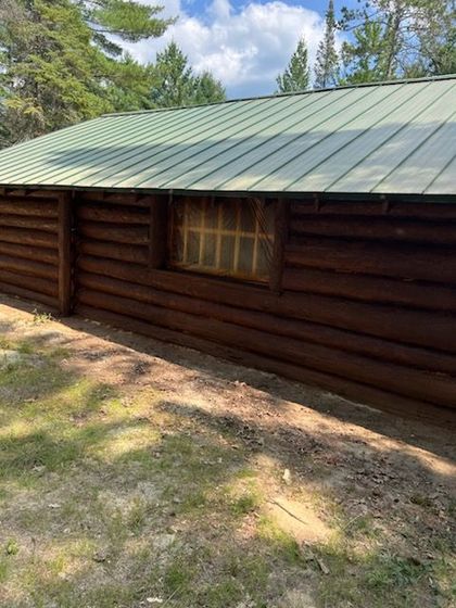A man with a beard is working on a log cabin