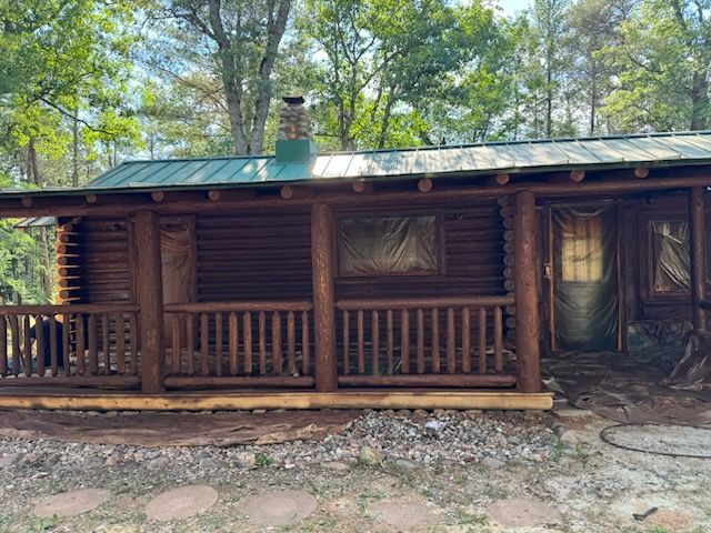 A log cabin with a porch in the woods.