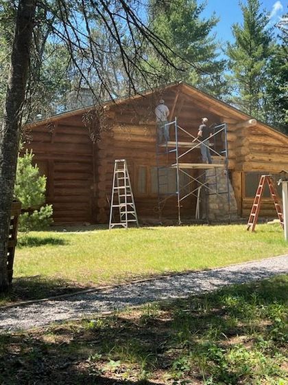 A large log cabin is sitting on top of a hill surrounded by trees.