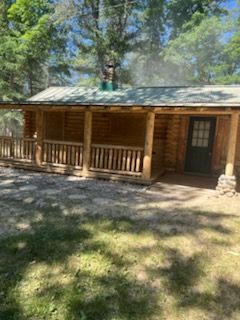 A log cabin with a porch and a chimney on the roof.