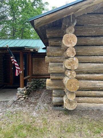 A log cabin with an american flag hanging from the roof.