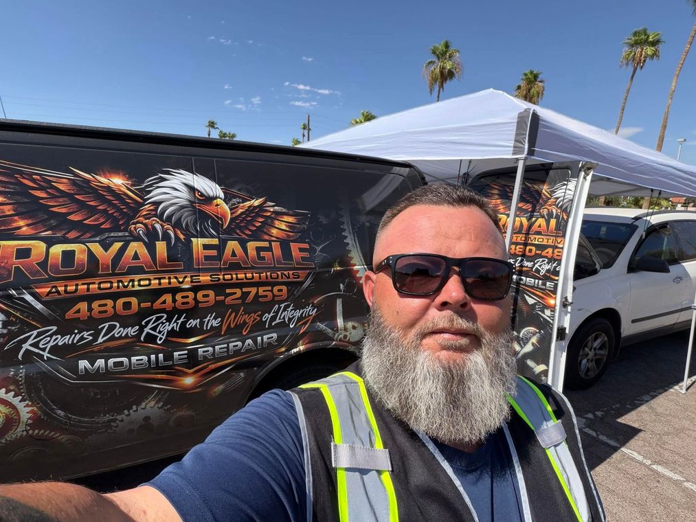 Man taking selfie in front of Royal Eagle tent and truck at an outdoor event, wearing sunglasses and a reflective vest