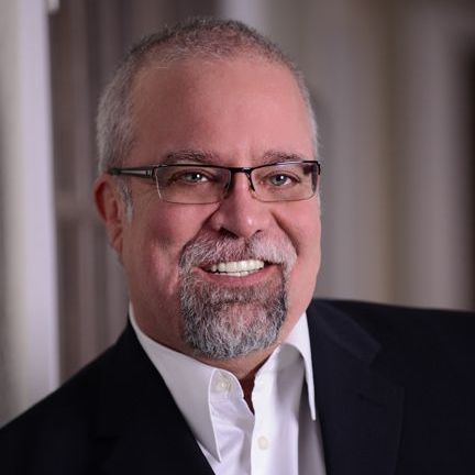 A man with a beard and glasses is smiling for the camera.