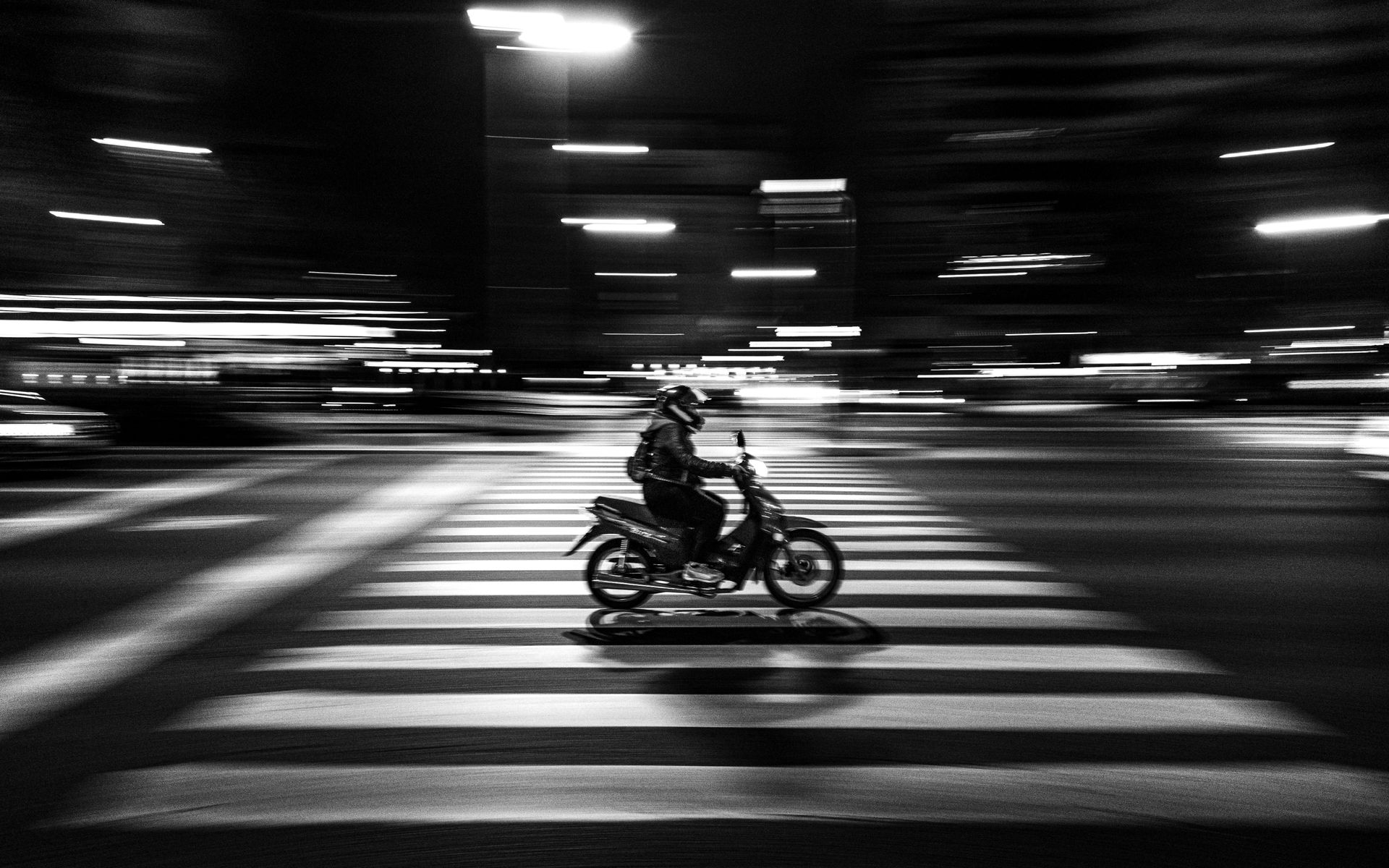 A person is riding a motorcycle on a crosswalk at night.