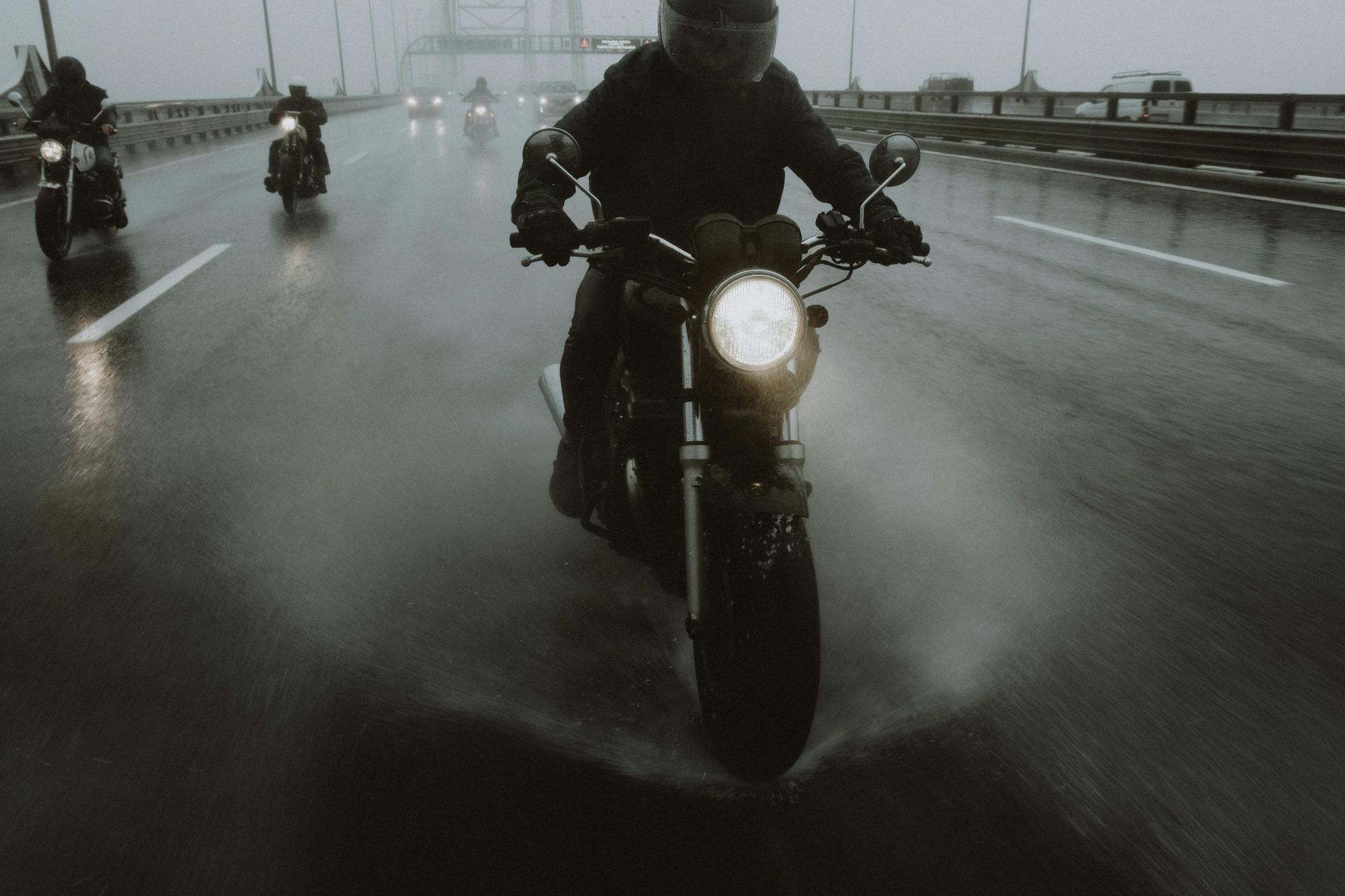 A man is riding a motorcycle on a wet highway.