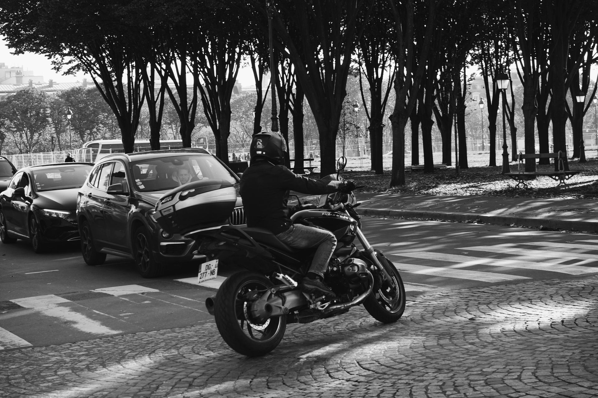 A man is riding a motorcycle down a street in a black and white photo.