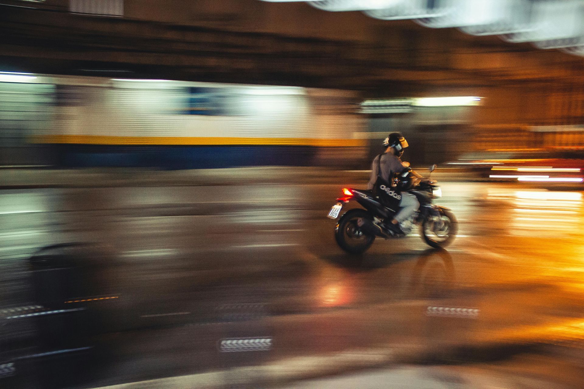 A person is riding a motorcycle down a wet street at night.