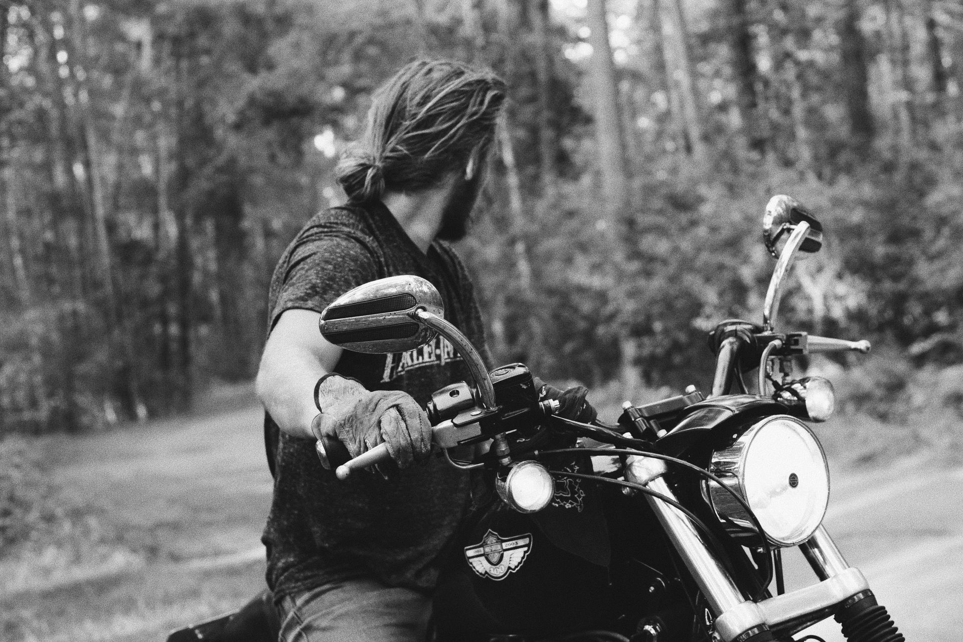 A man is riding a motorcycle down a road in the woods.