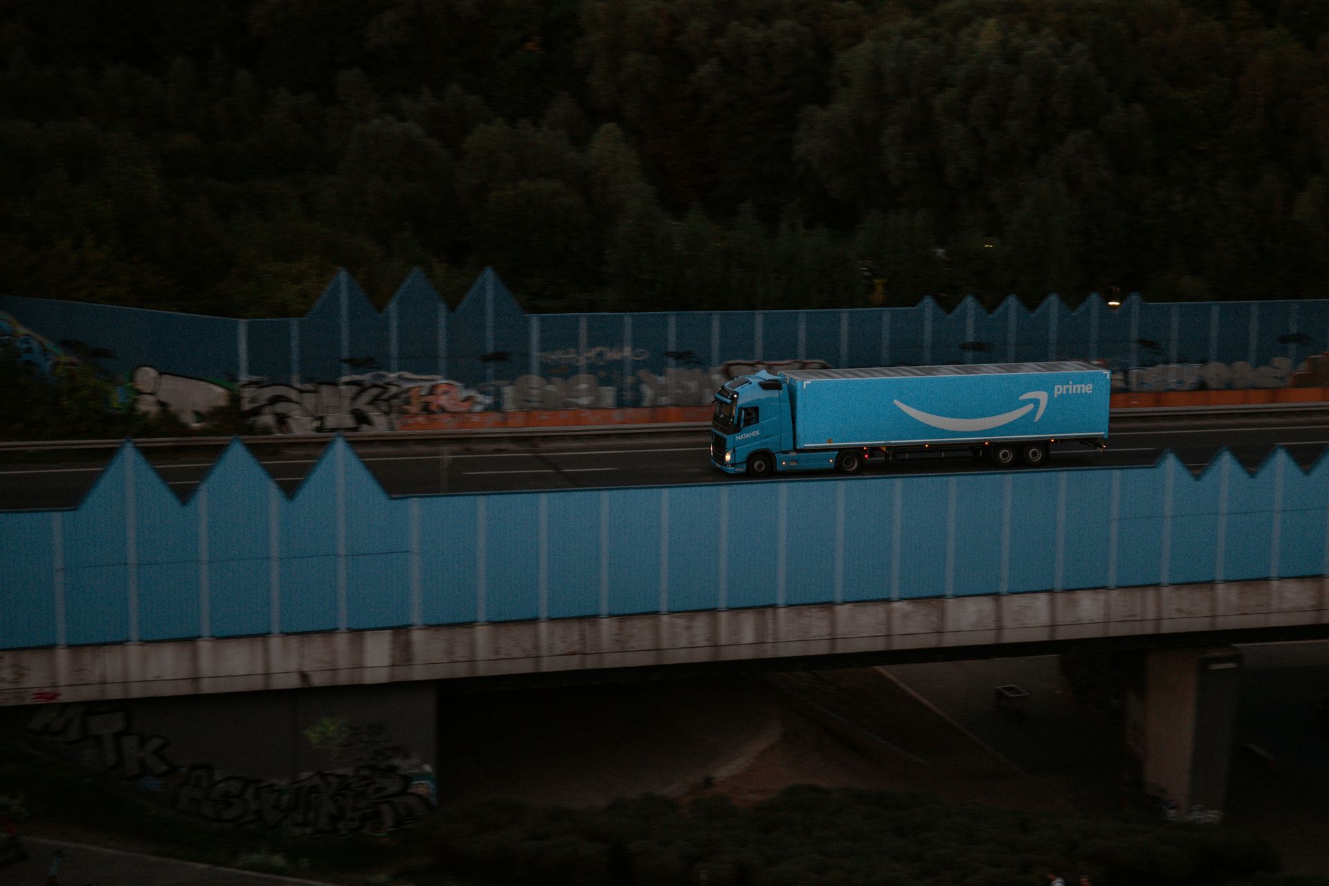 A blue amazon truck is driving on a highway at night.