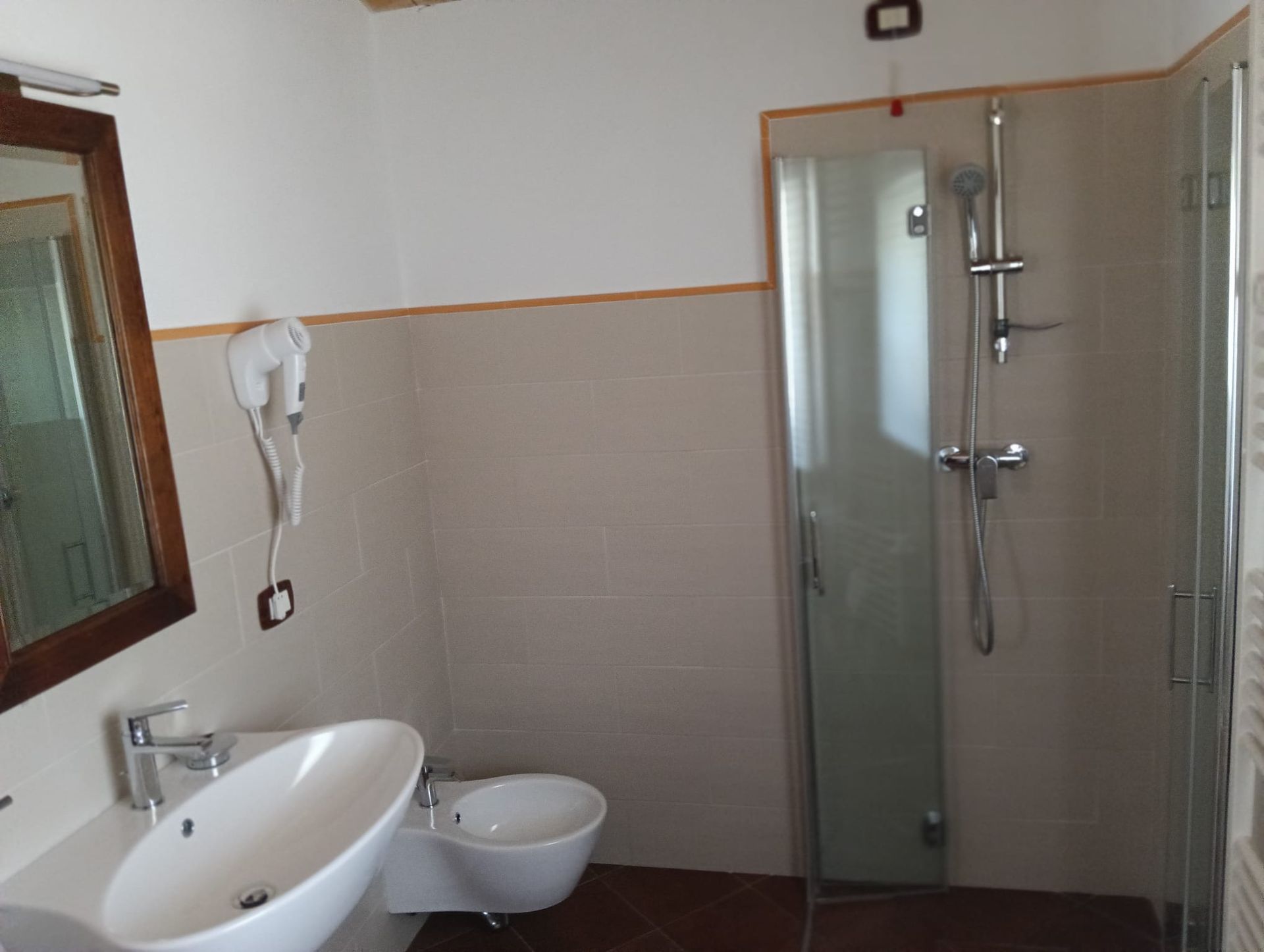 Bagno con doccia, lavandino, WC e specchio. Colori chiari, design semplice.