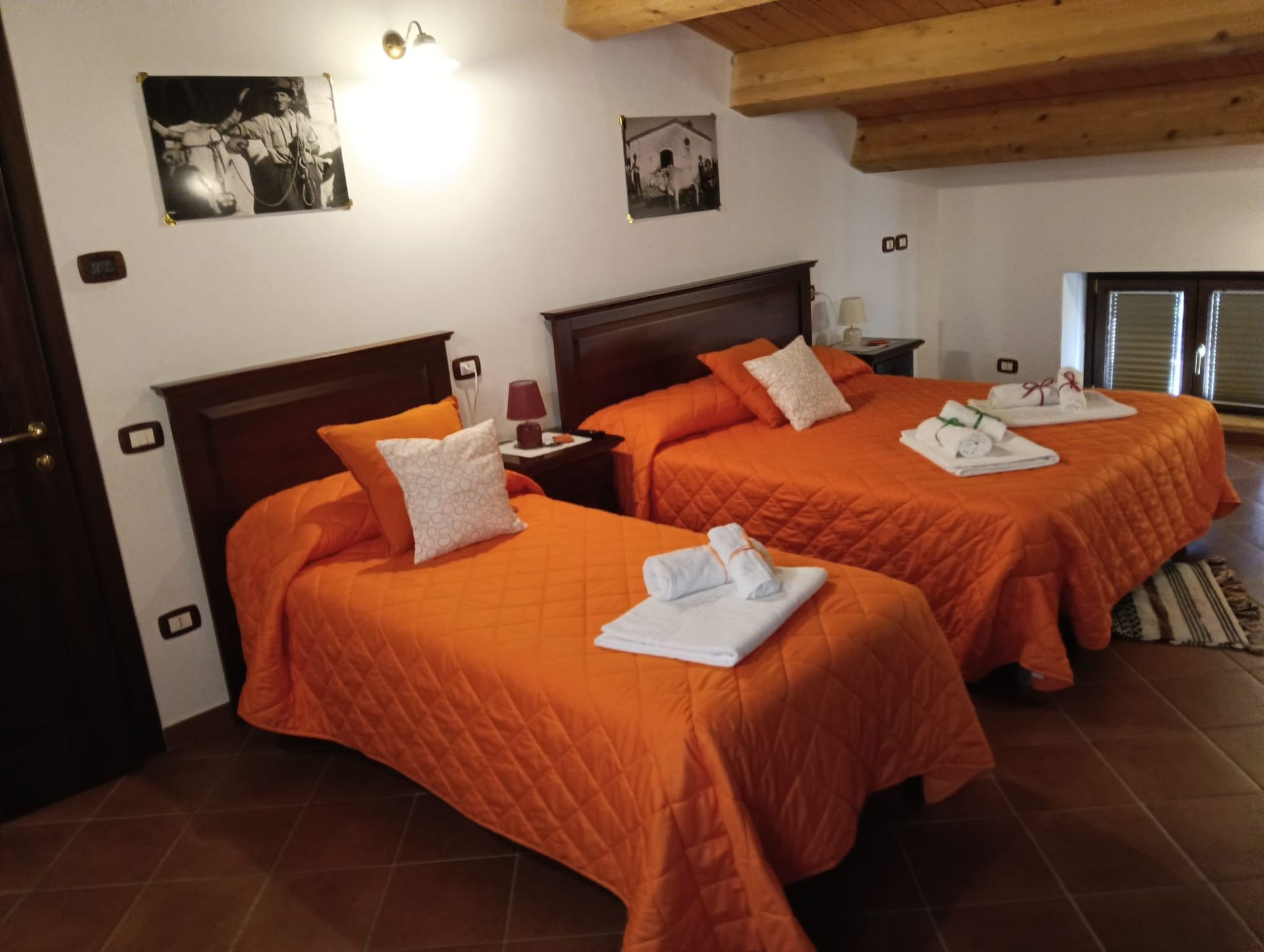 Camera da letto con un letto matrimoniale e un letto singolo, entrambi con biancheria da letto arancione.